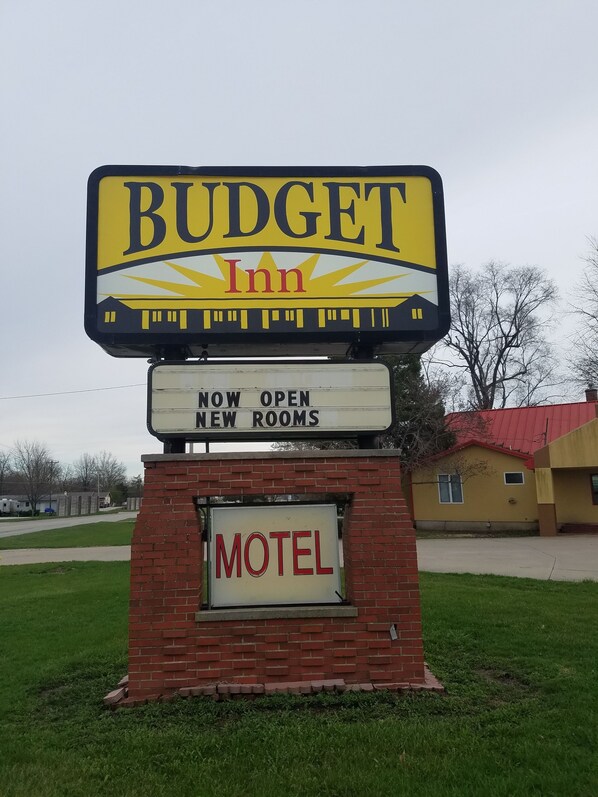 A motel sign with "BUDGET Inn" and "NOW OPEN NEW ROOMS" displayed.