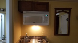 Una cocina compacta con microondas, estufa y lavamanos integrados.