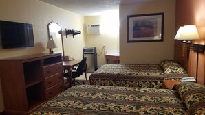 Habitación de hotel con dos camas, un escritorio con silla, televisión, lámpara de escritorio, microondas y un cuadro en la pared.