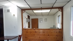 Un mostrador de recepción con panel de madera, suelo de baldosas, una silla y una puerta.