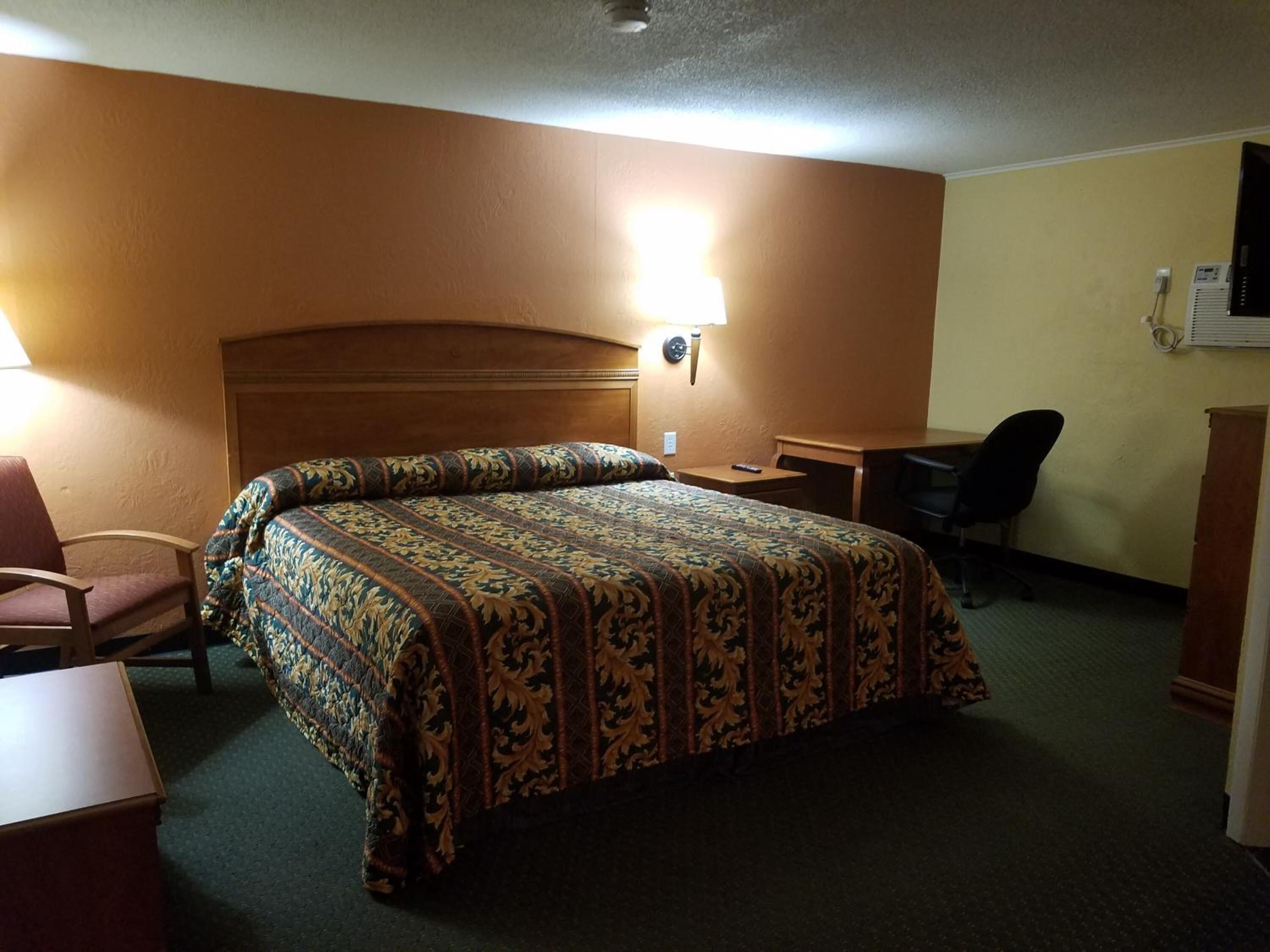 Habitación de hotel con una cama grande, un escritorio, una silla y un televisor.