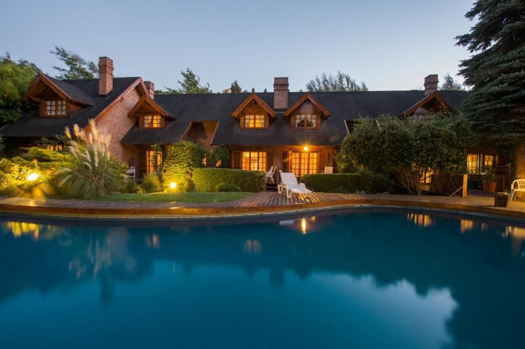 Una casa grande con piscina, varias chimeneas y un exterior bien iluminado.