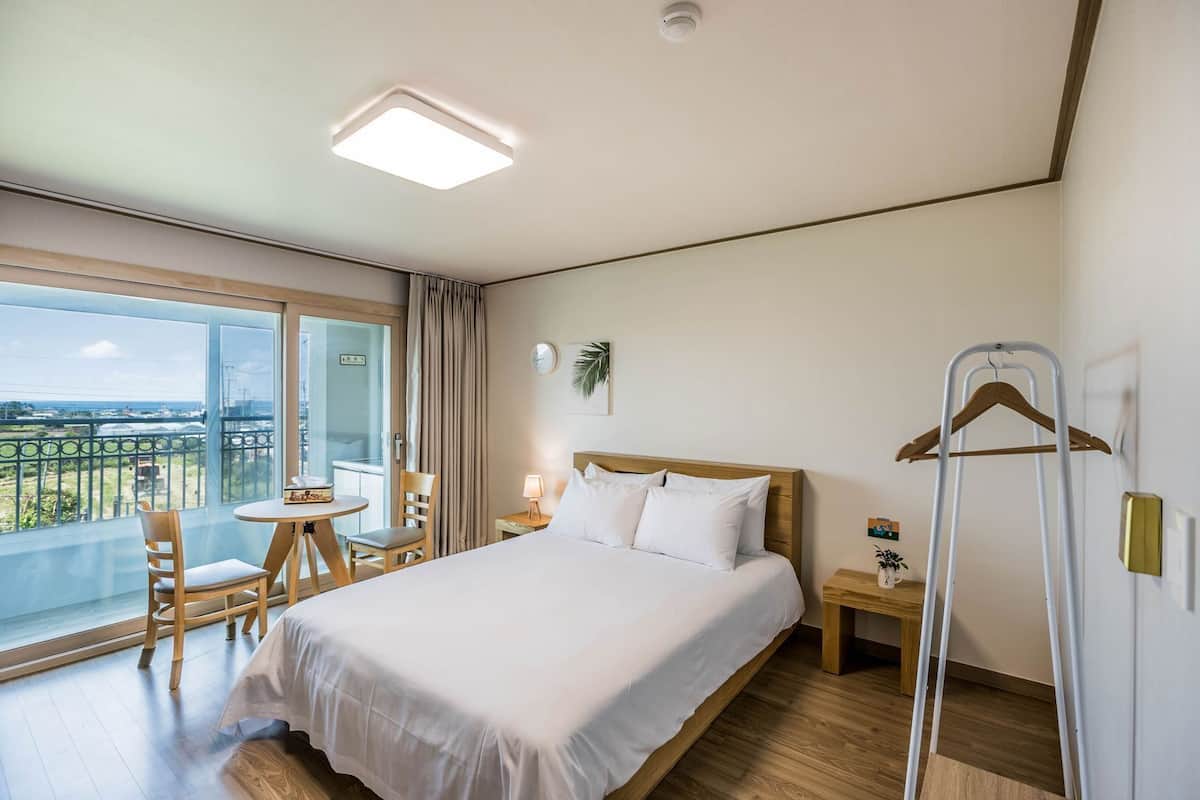 Habitación de hotel con cama, una mesa y sillas, balcón con vistas y perchero.