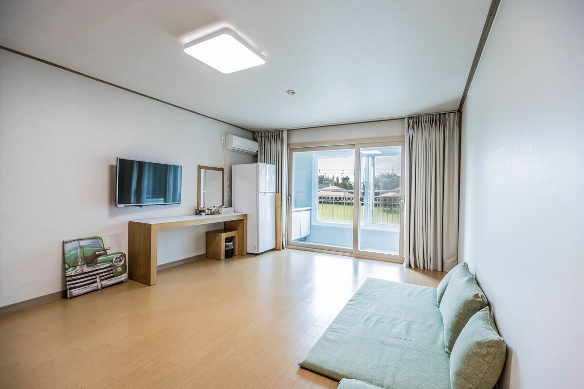 Una habitación de hotel moderna con una cama grande, un televisor de pantalla plana, un escritorio pequeño y una puerta corrediza de cristal a un balcón.