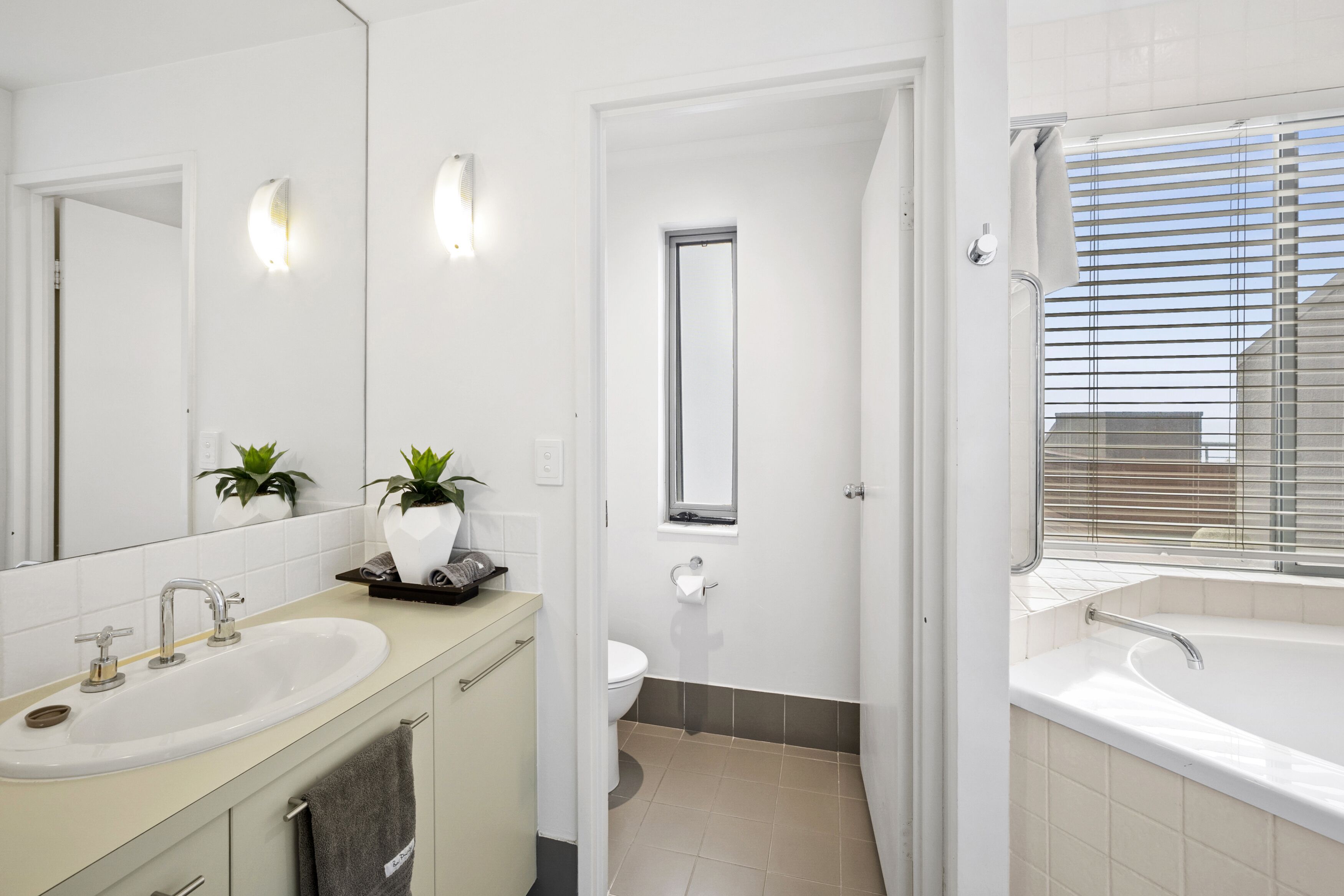 Une salle de bain moderne équipée d’un lavabo, d’un miroir, de toilettes et d’une baignoire.