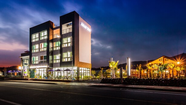 A multi-story hotel with a modern design, featuring a prominent 'AMAT HOTEL' sign. - Amantov Pension (Seogwipo)