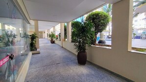 A corridor with potted plants, a glass wall, and a view of the outside. -  Apartamento Jardins das Thermas - Achei Férias (com roupa de cama) (Caldas Novas)