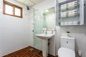 Ein modernes Badezimmer mit Duschkabine aus Glas, einem Standwaschbecken und einer Toilette.
