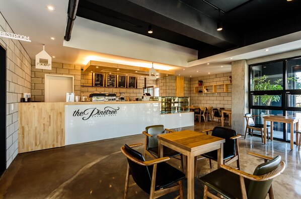 A modern cafe interior with a wooden counter, seating area, and a visible restroom sign. - Jeju Garden Pension (Seogwipo)