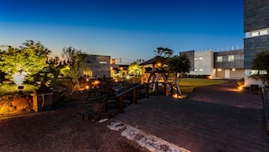 Un edificio moderno con terraza de madera y camino de piedra que conduce a la entrada.