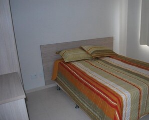 A bedroom with a bed, a headboard, and a wardrobe.