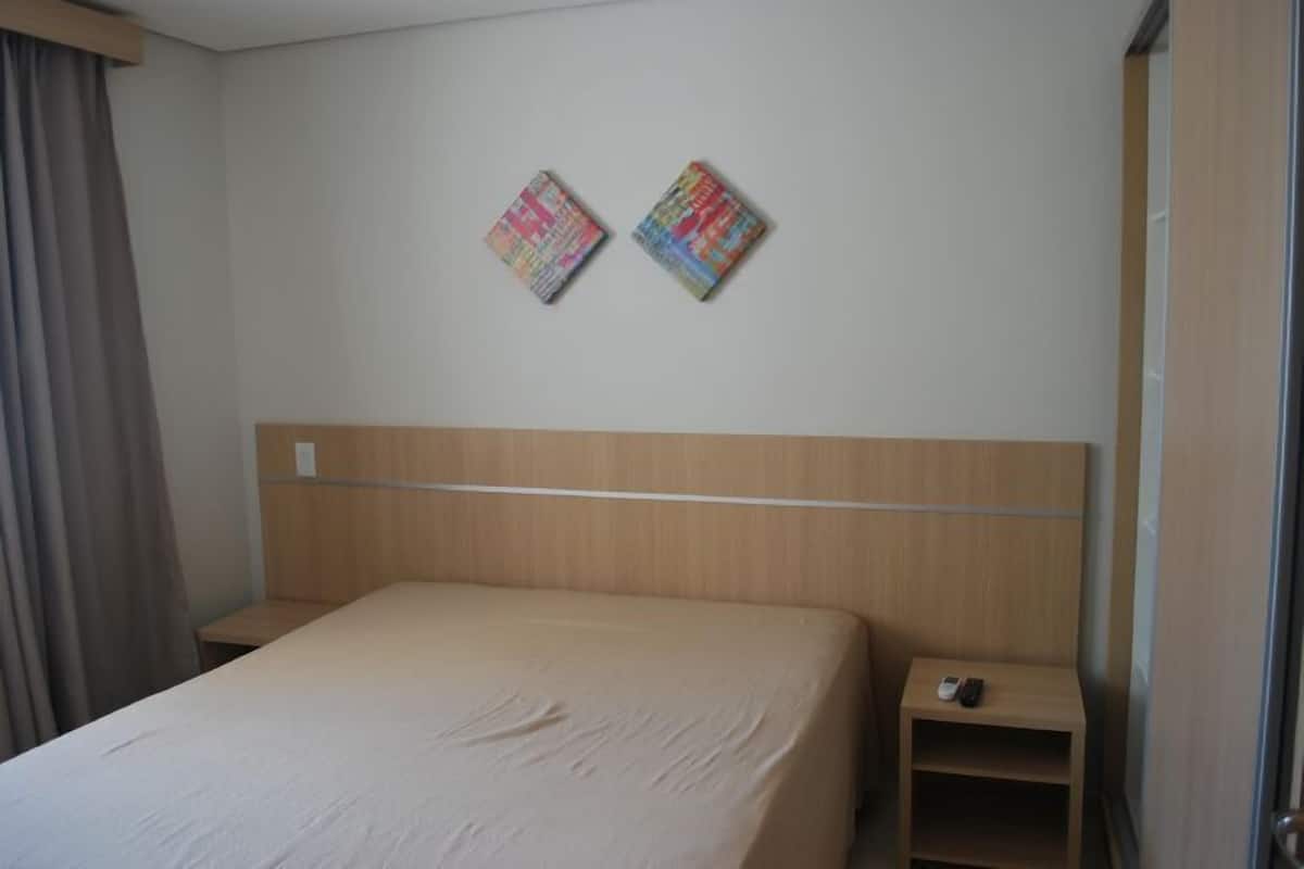 Una camera d'albergo con un letto singolo, una testiera in legno, due piccoli comodini e due elementi decorativi fissati alla parete.