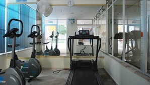 Un gimnasio con bicicletas estáticas, cintas de correr y un ventilador.