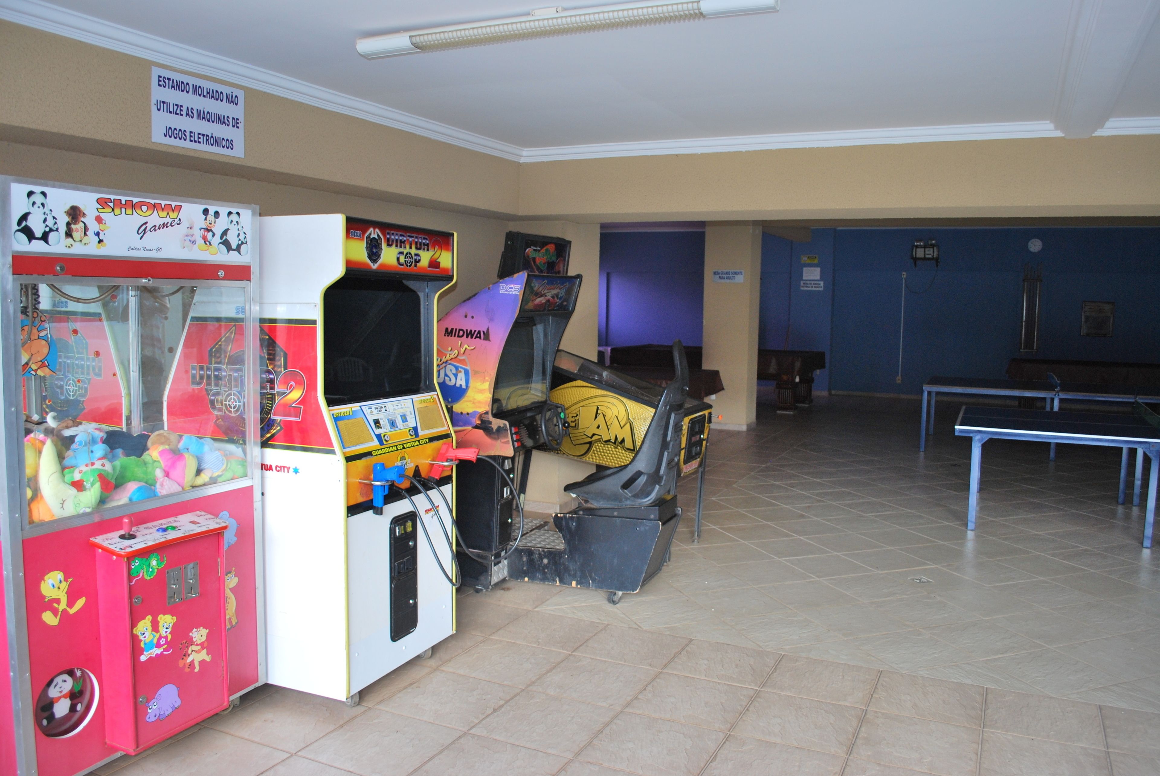 Une pièce avec des jeux d’arcade, une table de ping-pong et une porte bleue.