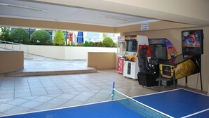 Una mesa de ping pong en un vestíbulo con juegos de arcade y una máquina expendedora.
