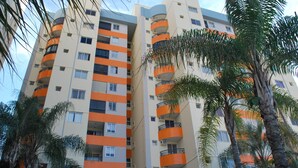 Un edificio residencial de varios pisos con balcones, rodeado de palmeras.