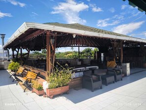 Un patio al aire libre con un área de estar techada, una mesa de billar y plantas en macetas.