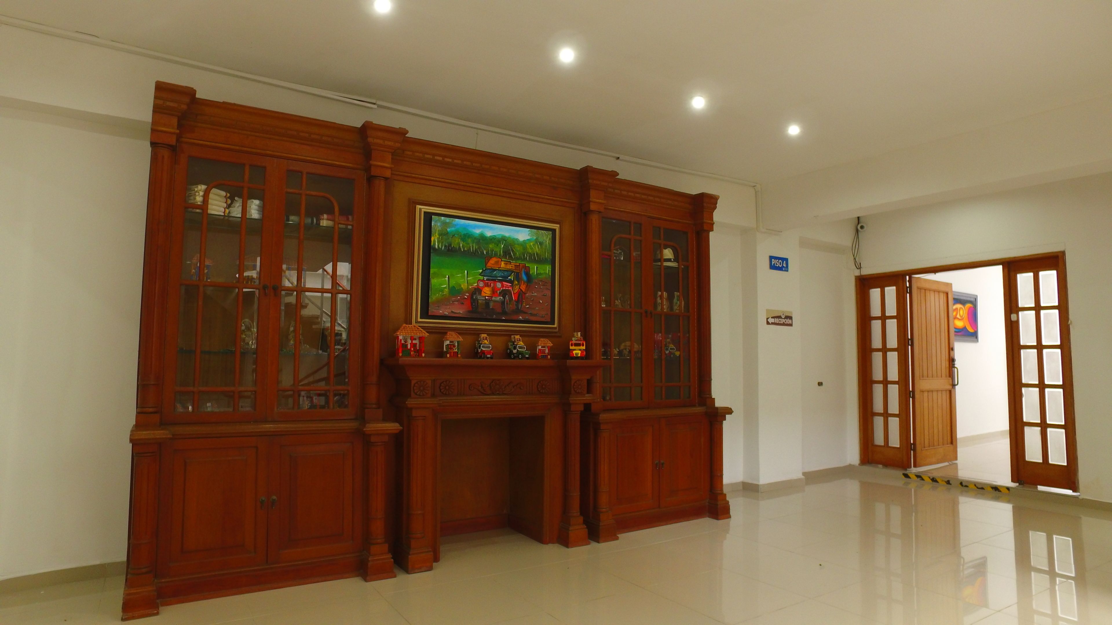 A spacious room with a polished floor, a wooden cabinet with glass doors, and a painting on the wall.