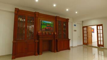 A spacious room with a polished floor, a wooden cabinet with glass doors, and a painting on the wall.