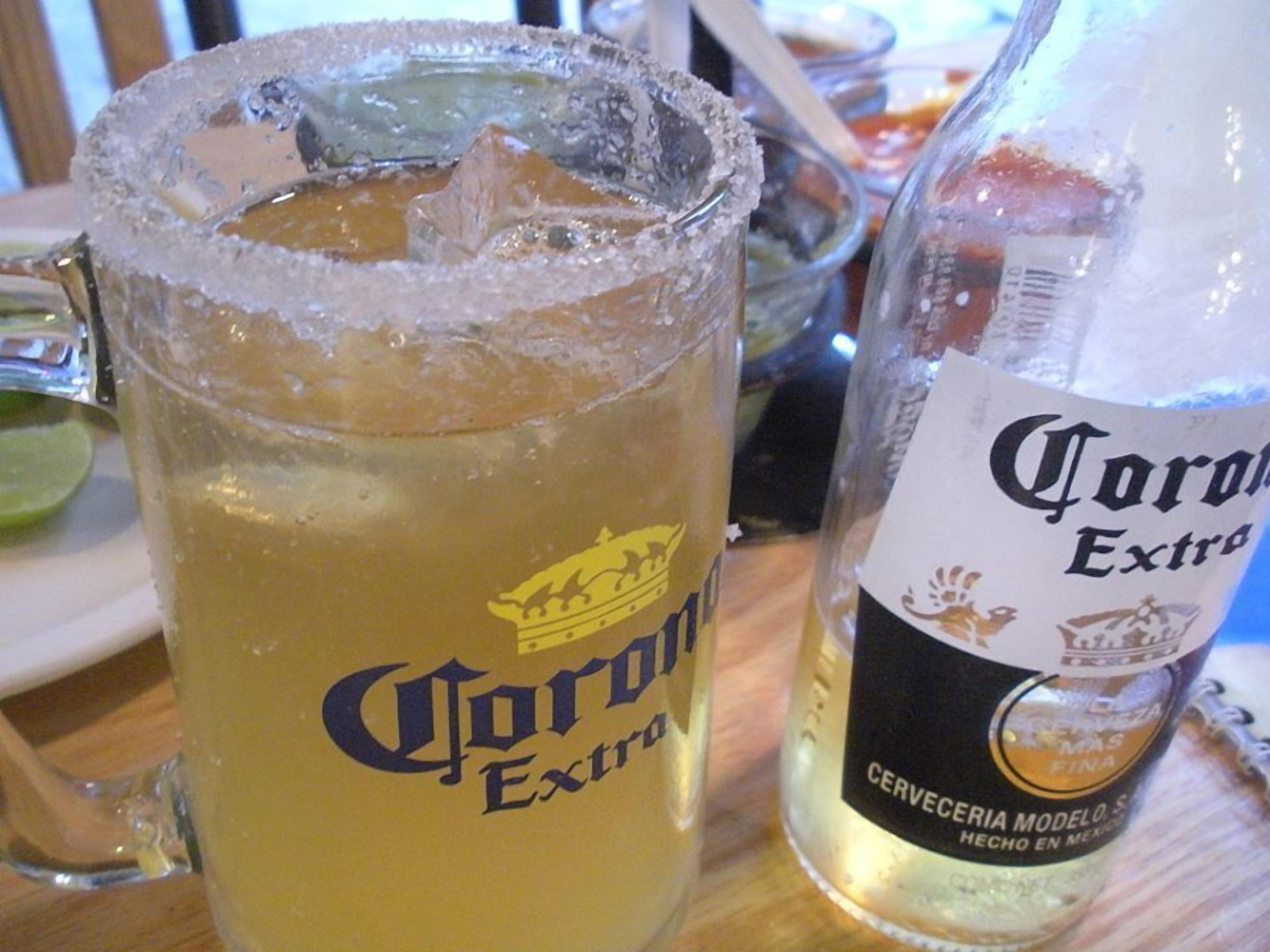 Un vaso con el logotipo de Corona Extra y una botella de cerveza Corona Extra.