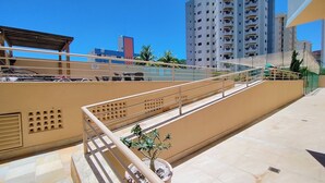 A multi-level outdoor area with a metal staircase, a small potted plant, and a building with multiple balconies in the background. - Thermas das Caldas - Achei Férias (Caldas Novas)