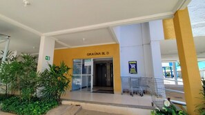 The entrance to a building with a yellow and white color scheme, a sign reading "GRAÚNA BL D", and a shopping cart near the entrance.