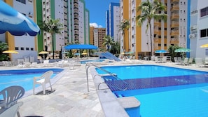 A resort pool area with multiple swimming pools, lounge chairs, and umbrellas.