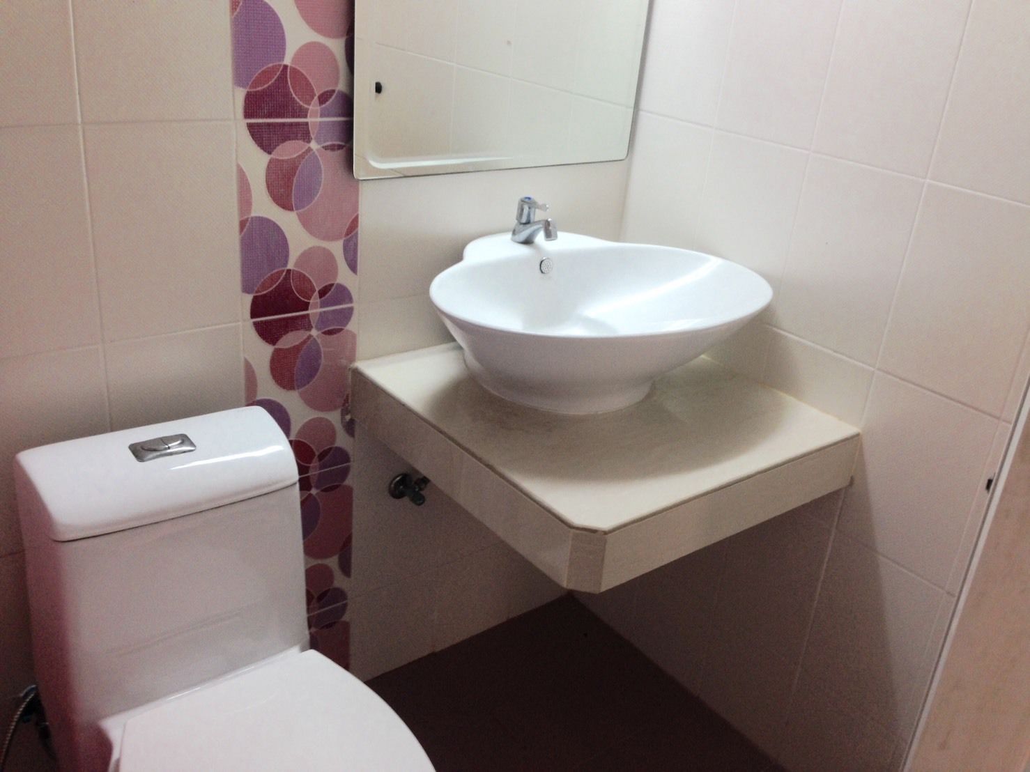 A bathroom with a toilet, a sink, and a mirror.