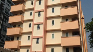 Un edificio residencial de varios pisos con balcones, un estacionamiento techado y un cielo despejado.