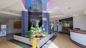 Un lobby moderno con una planta central, una mesa de recepción y un letrero para una tienda de plantas.