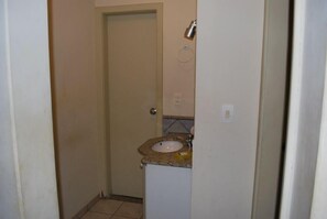 A small bathroom with a sink, a door, and a light fixture.