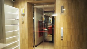 A hotel elevator with a mirrored wall, a phone, and a control panel. - Big Zen Condotel (Nonthaburi)