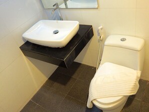 A bathroom with a white sink, black countertop, and a white toilet. - Big Zen Condotel (Nonthaburi)