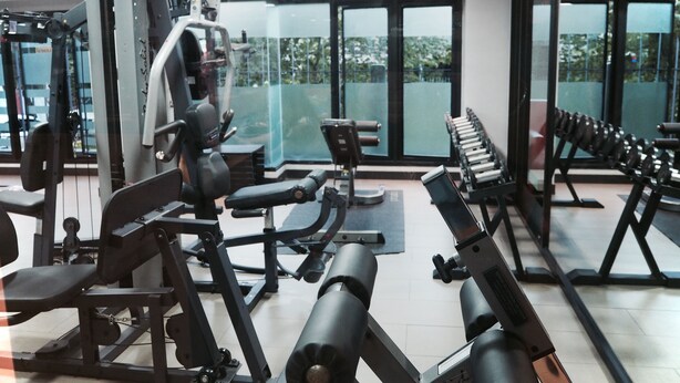 A gym with various exercise equipment, large windows, and a view of greenery outside. - Big Zen Condotel (Nonthaburi)