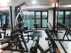 A gym with various exercise equipment, large windows, and a view of greenery outside. - Big Zen Condotel (Nonthaburi)