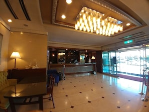 A hotel lobby with a reception desk, seating area, and a chandelier. - Prime Tourist Hotel (Busan)