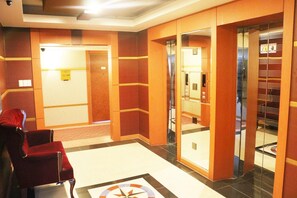 Un hall d’hôtel avec un tapis rouge, un comptoir d’accueil et un ascenseur.