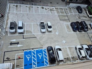 An aerial view of a parking lot with multiple rows of parked cars, directional arrows, and blue handicap parking spaces.