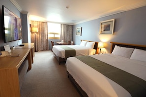 A hotel room with two beds, a desk, a TV, and a window with curtains. - Prime Tourist Hotel (Busan)