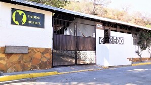 A Tadeo Hostel with a stone wall entrance, a metal gate, and a corrugated metal roof. - Hostel Tadeo San Juan del Sur (San Juan del Sur)