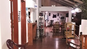 A spacious indoor area with wooden flooring, multiple seating arrangements, and a high ceiling with exposed beams. - Hostel Tadeo San Juan del Sur (San Juan del Sur)
