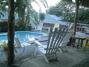 Un área de piscina con sillas de descanso y una pequeña mesa.