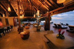 A beachside lounge with thatched roof, lounge chairs, and a view of the ocean. - Tides Reach Resort (Taveuni Island East)