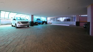 Amplio estacionamiento techado con un coche blanco y una camioneta azul.
