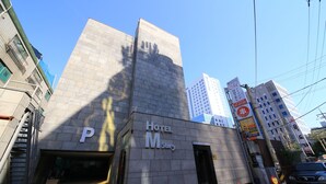 Un moderno edificio de hotel con un letrero grande con la letra 'P' que indica estacionamiento.