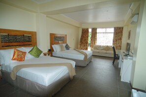 A hotel room with two beds, a sofa, a desk, and a window with curtains. - Jezami Hotel (Nuku'alofa)