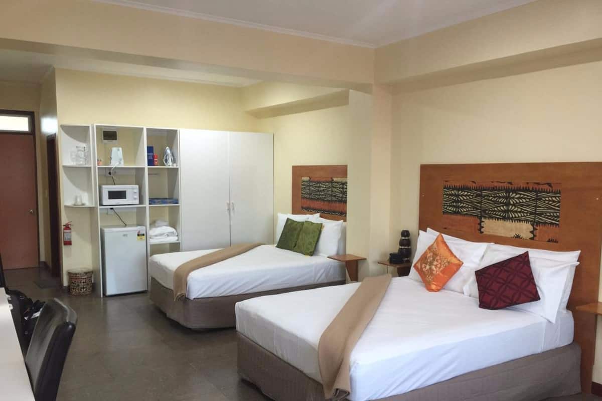 A hotel room with two beds, a wardrobe, a microwave, and a small refrigerator.