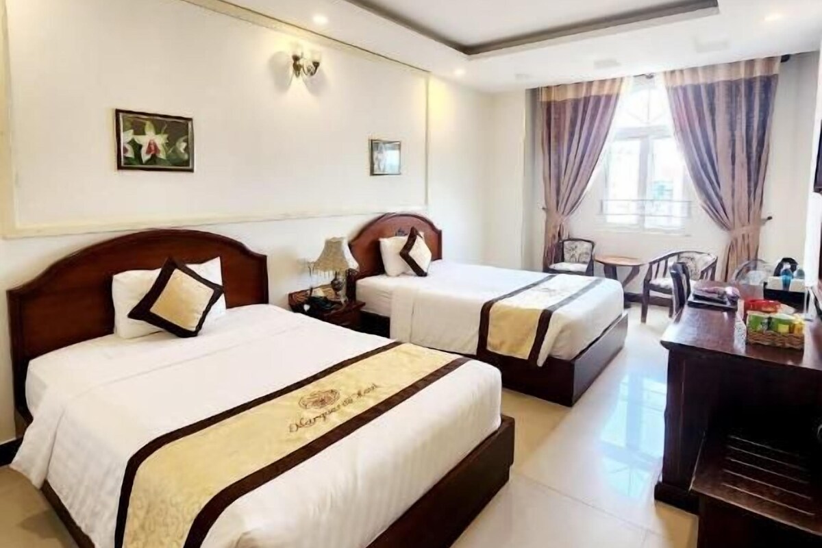 A hotel room with two beds, a desk, and a chair.