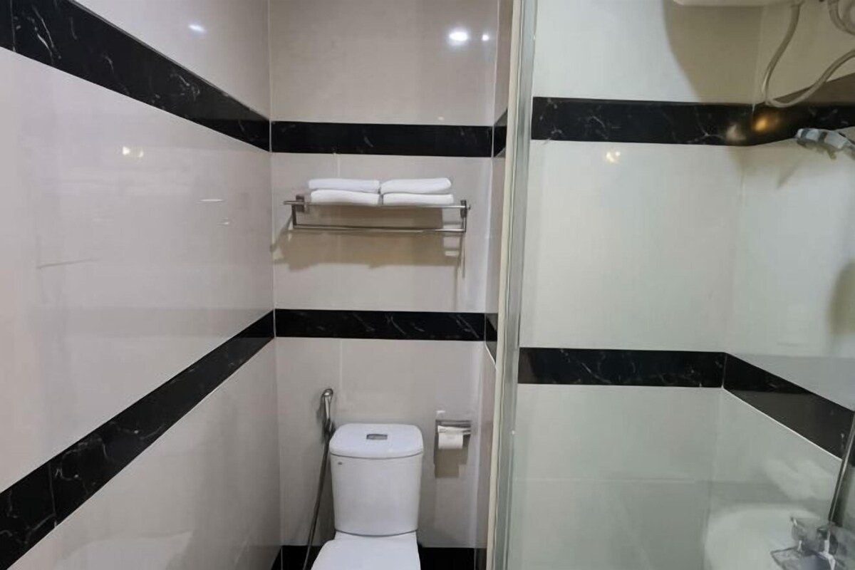 A bathroom with a toilet, a towel rack, and a shower area.