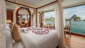 Une chambre à coucher luxueuse, dotée d’un grand lit, d’un plancher en bois et offrant une vue sur la mer et les falaises.